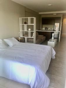 a bedroom with a large white bed and a couch at Edificio fresh pampa in Buenos Aires