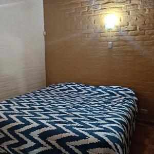 a bed in a room with a light on a brick wall at La Bohemia in Las Compuertas