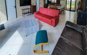 ein Wohnzimmer mit einem roten Sofa und einem blauen Stuhl in der Unterkunft Gorgeous Home In Bacilly With Kitchen in Bacilly