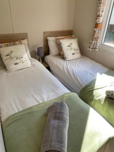 two beds in a room with a persons leg on the bed at Tranquil Retreat at River Valley Country Park in Penzance