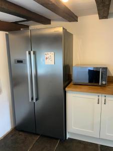 a stainless steel refrigerator in a kitchen with a microwave at Delightful 4BD Home full of Flair Edenbridge Kent in Edenbridge
