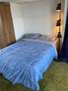 Una cama con una manta azul encima. en Luc's place, Waterbed grote kamer, en Zoeterwoude