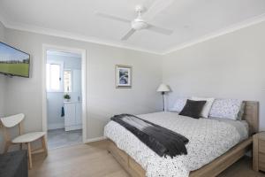 ein weißes Schlafzimmer mit einem Bett und einer weißen Decke in der Unterkunft Camellia Cottage in Berrima