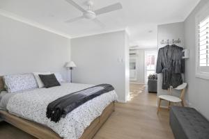 a white bedroom with a bed and a chair at Camellia Cottage in Berrima