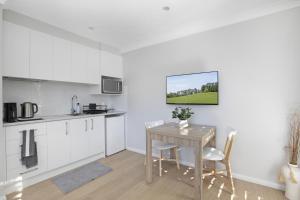 a kitchen with white cabinets and a table with chairs at Camellia Cottage in Berrima