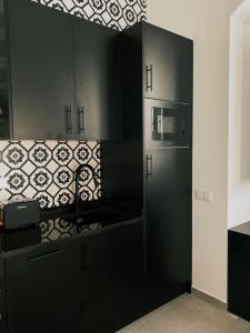 a kitchen with black cabinets and a microwave at Baixa-Mar Setúbal Miradouro in Setúbal