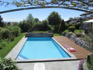 a swimming pool in a yard with a wooden deck at B&B Pension Marina in Rüttenen  