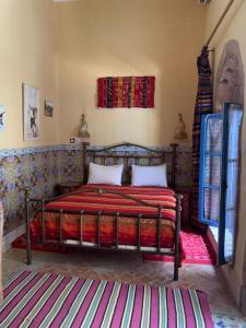 a bedroom with a bed with a red bedspread at Riad Le Cheval Blanc in Safi