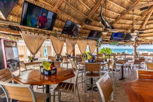 フォート・ローダーデールにあるOcean Beach Condo 3BR On the Sand 811の天井にテーブルと椅子、テレビが備わるレストラン