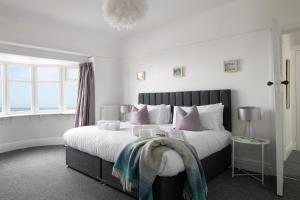a bedroom with a large bed with pink pillows at Beachcliffe House - Sea front property - Sleeps 10 - Pet friendly in Llandrillo-yn-Rhôs