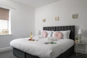 a bedroom with a large white bed with pink pillows at Beachcliffe House - Sea front property - Sleeps 10 - Pet friendly in Llandrillo-yn-Rhôs