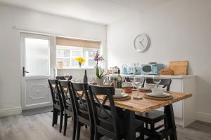 a dining room with a table with chairs and a clock at Beachcliffe House - Sea front property - Sleeps 10 - Pet friendly in Llandrillo-yn-Rhôs