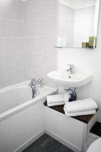 a white bathroom with a sink and a bath tub at Hôtel Restaurant Gédéon in Carnon-Plage