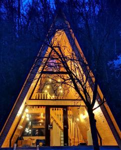 una casa con un techo triangular por la noche en Casa - Cabana Tip A Frame, Cerna, Vaideeni, Valcea, en Cerna