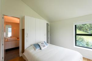 a white bedroom with a bed and a window at Sete Cidades Lake Cabin - Casa da Lagoa in Ponta Delgada