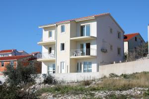 un edificio blanco en la colina con casas en el fondo en Apartments by the sea Businci, Ciovo - 4863, en Trogir