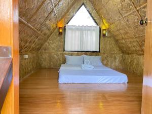 Cama en habitación pequeña con ventana en Don Roberto's Kubo Resort, en Nasugbu