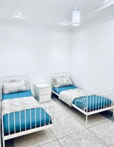 two beds in a room with white walls at Résidence Bario H in Al Hoceïma
