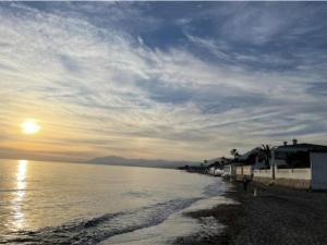 een strand met zonsondergang boven het water bij Bright & Modern 2 Bedroom Apartment 300m to the Beach - Marbella in Marbella