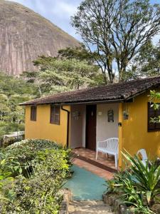 uma casa amarela com um banco no alpendre em Casa do lenhador em Petrópolis