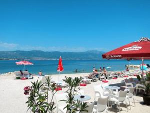 una playa con sillas, mesas y una sombrilla roja en Apartments by the sea Arbanija, Ciovo - 6062, en Trogir