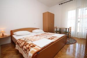 a bedroom with a bed and a table and a window at Apartments and rooms by the sea Seline, Paklenica - 6440 in Starigrad-Paklenica