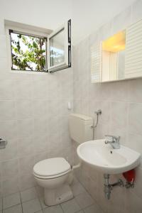 a white bathroom with a toilet and a sink at Apartments and rooms by the sea Seline, Paklenica - 6440 in Starigrad-Paklenica