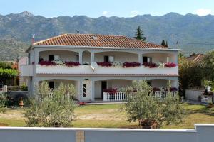 a white house with flowers on the front of it at Apartments with a parking space Seline, Paklenica - 6603 in Starigrad