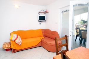 ein Wohnzimmer mit einem orangenen Sofa und einem TV in der Unterkunft Apartments with a parking space Seline, Paklenica - 6603 in Starigrad-Paklenica