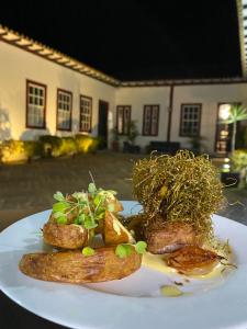 um prato de alimentos com carne e batatas numa mesa em Pousada Travessia - Minas Gerais em Três Pontas