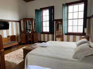 a bedroom with a bed and a tv and windows at Pousada Travessia - Minas Gerais in Três Pontas