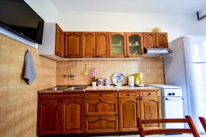 eine Küche mit Holzschränken, einer Spüle und einem Kühlschrank in der Unterkunft Apartments with a parking space Zadar - Diklo, Zadar - 6453 in Diklo
