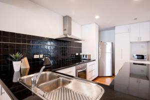 a kitchen with a sink and a stainless steel refrigerator at Chic Harbourside Group Haven in Heart of Hobart in Hobart +10 photos