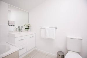 a white bathroom with a toilet and a sink at Chic Harbourside Group Haven in Heart of Hobart in Hobart