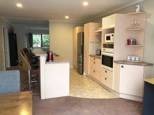 a kitchen with white cabinets and a counter top at Observation Holiday Home in Paraparaumu Beach
