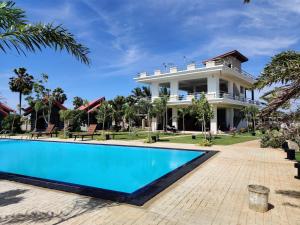 una casa grande con piscina frente a ella en Anukama Resort, en Nilaveli