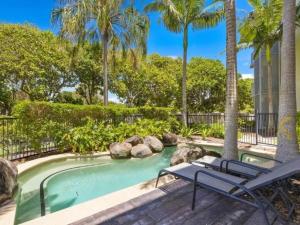 a swimming pool with two chairs and palm trees at Tranquil Spa Suite, K-bed, Plunge Pool at Kingscliff Salt Beach Resort and Spa in Kingscliff