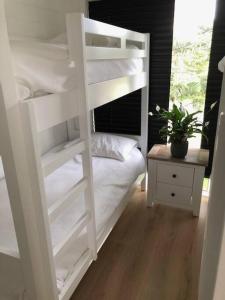 białe łóżko piętrowe w sypialni z doniczką w obiekcie Jetty Road Beach House w mieście Rosebud