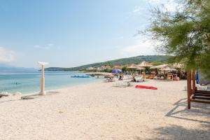 a beach with chairs and umbrellas and the ocean at Apartments by the sea Slatine, Ciovo - 9454 in Slatine