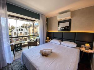 - une chambre avec un grand lit blanc et une grande fenêtre dans l'établissement LOCAR-IN GRAMADO- 100m Rua Coberta, à Gramado