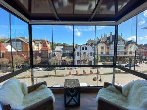 Zimmer mit 2 Stühlen und einem großen Fenster in der Unterkunft LOCAR-IN GRAMADO- 100m Rua Coberta in Gramado
