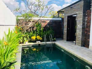 una piscina en un jardín con un edificio de ladrillo en Villa Triyuna, our little paradise, en Banjar