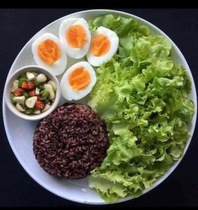 a plate of food with eggs and lettuce and beans at Moon Light Guest House in Tissamaharama