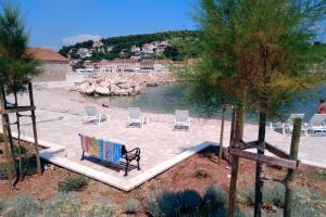 een bankje op een zandstrand naast het water bij Holiday house with a swimming pool Vrbanj, Hvar - 11040 in Vrbanj