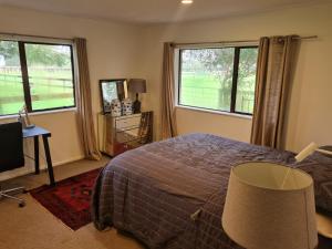 a bedroom with a bed and two windows and a television at Five paddocks Tamahere in Tamahere