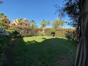 een tuin met een heg en palmbomen en een gebouw bij atlas golf resort marrakech " Maison à 03 chambres avec jardin privé " in Marrakesh