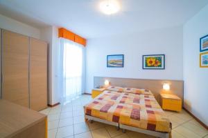 a bedroom with a bed and two tables and a window at Aparthotel Gioia in Caorle