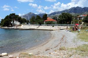 a group of people sitting on a beach near the water at Apartments with a parking space Seline, Paklenica - 6628 in Starigrad
