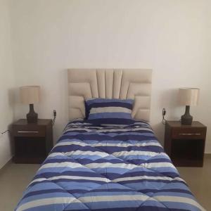 a bedroom with a blue and white bed with two lamps at Casa-Posada in Cajamarca