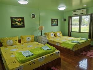 duas camas num quarto com paredes verdes em Bussaracum Resort em Kanchanaburi